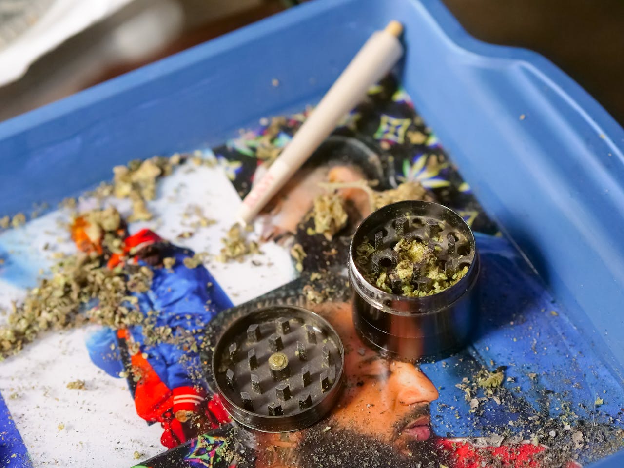 services-01 Cannabis grinder filled with marijuana next to a rolled joint on a colorful tray. Perfect for cannabis culture imagery.